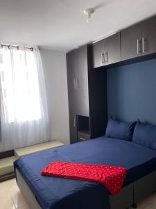 ein Schlafzimmer mit einem blauen Bett und einem roten Kissen darauf in der Unterkunft APARTAESTUDIO EN ORO NEGRO OCASO ARMENIA QUINDIO in Armenia