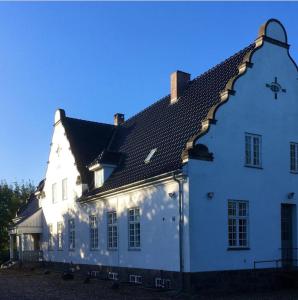 ein großes weißes Gebäude mit schwarzem Dach in der Unterkunft Jungshovedgaard Bed & Breakfast in Præstø