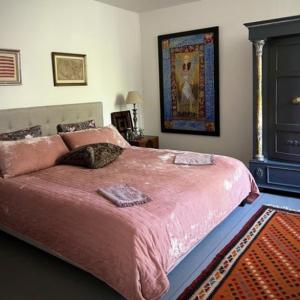 ein Schlafzimmer mit einem großen Bett mit einer rosa Decke in der Unterkunft Jungshovedgaard Bed & Breakfast in Præstø