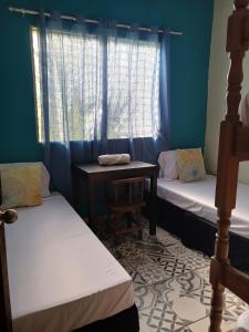a room with two beds and a table and a window at El Rancho De Don Moncho Hostel 