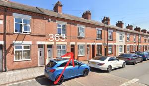 um carro azul estacionado em frente a um edifício de tijolos em Tudor Road House em Leicester