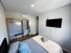 a bedroom with a bed and a flat screen tv at Lindo apartamento a 400 metros da praia com selo azul de qualidade in Governador Celso Ramos