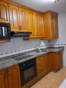 uma cozinha com armários de madeira, um lavatório e um fogão em Carmina fondon 3 em Cangas de Onís