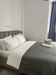 - une chambre avec un lit doté de draps et d'oreillers blancs dans l'établissement Regal Apartment 2, à Tirana