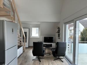 a living room with two chairs and a desk and a refrigerator at Ferienwohnung Ulrich Gebauer in Bad Staffelstein