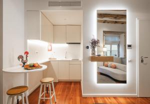 a kitchen with white cabinets and a table and stools at Bandeiras in Porto