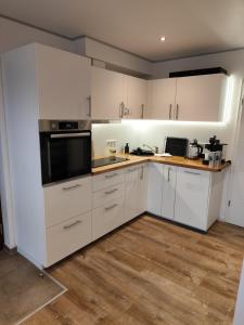 a kitchen with white cabinets and a wooden floor at Ferienhaus Liewer 