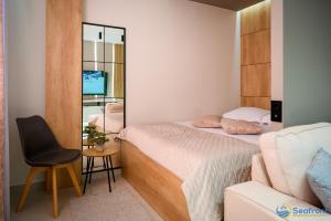 a bedroom with a bed and a chair and a mirror at Seafront Residence Makarska in Makarska