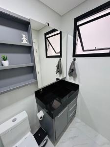 a bathroom with a toilet and a sink and a window at Lindo apartamento a 400 metros da praia com selo azul de qualidade in Governador Celso Ramos +22 photos