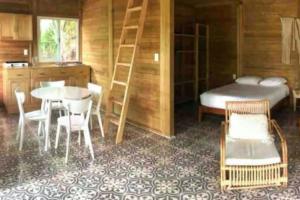 Habitación con cama, mesa y sillas. en Cabañas Sukha Bacalar, en Bacalar