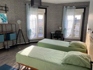 2 Betten in einem Zimmer mit 2 Fenstern in der Unterkunft Maison de ville au centre de Fismes in Fismes
