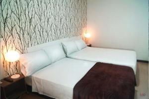 una camera con un letto, due lampade e una parete di HOTEL ALCUARA a Pereira