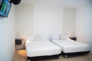Habitación con 2 camas individuales y TV. en HOTEL ALCUARA, en Pereira
