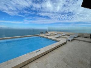 a swimming pool with lounge chairs and the ocean at U-GO Edificio Murano Elite Bocagrande Frente al Mar in Cartagena de Indias