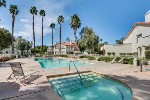 a swimming pool with two chairs and palm trees at Palm Desert Condo with Patio and Community Perks! in Palm Desert