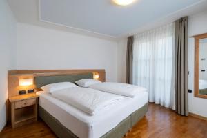 Schlafzimmer mit einem großen weißen Bett und einem Fenster in der Unterkunft Hotel Erica in Tesero