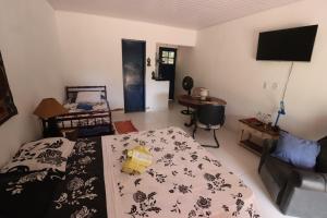 a bedroom with a bed and a couch and a television at Estalagem do Rancho in Miguel Pereira