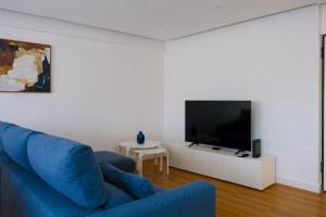 uma sala de estar com um sofá azul e uma televisão em Blue Dreams em Queluz