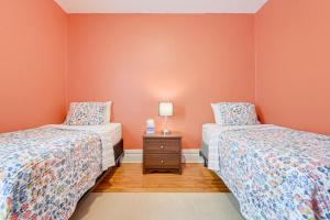 two beds in a room with orange walls at Buffalo Apt with Balcony about 3 Mi to Downtown! in Buffalo