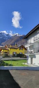 a yellow house with mountains in the background at Appartamento Due Laghi in Tenno +14 photos