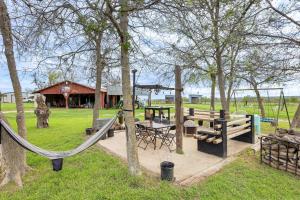 a playground in a park with a swing at Texas Farmhouse on 14 Acres with Pond Access! 