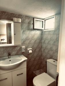 ein Badezimmer mit Waschbecken und Toilette und einem Fenster in der Unterkunft NIKOS SEA VIEW ROOM in Kallithea (Chalkidiki)