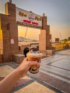 a hand holding a cupcake in front of a building at Salah El Din Restaurant on the Nile Corniche in Aswan