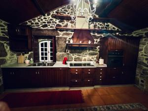 a kitchen with wooden cabinets and a stone wall at QUINTA DONA MANUELA in Formariz