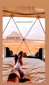 a person laying on a bed in a tent at Lukasa camp Wadi Rum in Wadi Rum