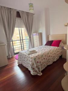 Schlafzimmer mit einem Bett mit roten Kissen und einem Fenster in der Unterkunft Apartamento Boiro centro in Boiro