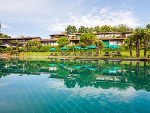 un complejo con una gran piscina de agua con sillas y sombrillas en Park Hotel Principe - Ticino Hotels Group, en Lugano
