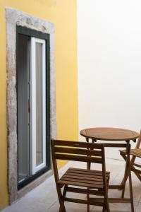 uma mesa de madeira e cadeiras ao lado de uma mesa e uma janela em The Haus - Alegria em Lisboa