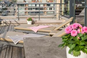 un tavolo e sedie su un balcone con fiori rosa di Ruim appartement met heerlijk zonneterras a Bruges