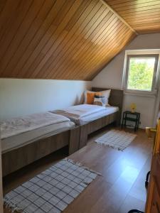 2 camas en una habitación con techo de madera en Zita Vendégház, en Dombóvár