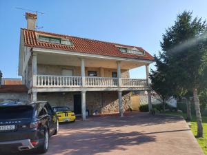 a house with a balcony and a car parked in front at Precioso chalet cerca de la playa de Samil in Vigo