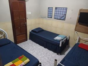 a room with two beds and a tv and windows at Pousada Mara Mar Niterói in Niterói