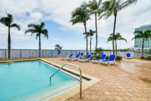 a swimming pool with lounge chairs and palm trees at Riverfront Fort Myers Condo with Community Amenities in Fort Myers