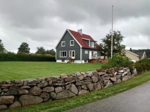 a gray house with a red roof and a stone wall at Duveslätt B & B in Åskloster
