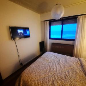 1 dormitorio con 1 cama, TV y ventana en Arpon 9 - 5C - Frente al mar 2 dorm. cochera privada en Villa Gesell