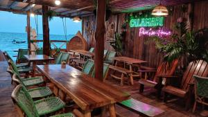 a restaurant with wooden tables and chairs and the ocean at Hotel Calamari Baru in Playa Blanca