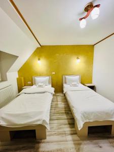ブカレストにあるHotel Marina srlの黄色い壁の客室で、ツインベッド2台が備わります。