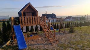 a wooden playground with a blue slide and a ladder at Domki Pod Łysicą in Krajno Pierwsze