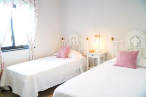 two beds in a white room with pink pillows at Villa Marrachinho in Albufeira