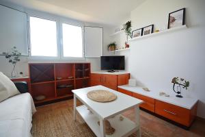 ein Wohnzimmer mit einem Sofa und einem Tisch in der Unterkunft Apartamento con jardín en Playa de Corrubedo in Ribeira
