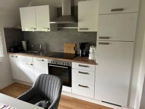 a kitchen with white cabinets and a chair in it at Idyllische Ferienwohnung in Wiefelstede in Wiefelstede