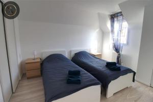 1 dormitorio con 2 camas con sábanas azules y ventana en Maison 6 personnes à 4 KMS de DISNEY, en Magny-le-Hongre