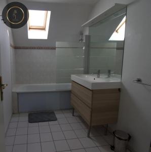 bagno con lavandino, vasca e specchio di Maison 6 personnes à 4 KMS de DISNEY a Magny-le-Hongre