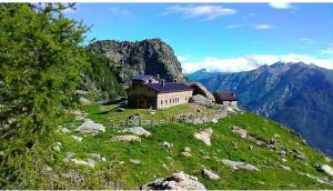 un edificio en la cima de una colina con una montaña en Rifugio Alpe Bonze, en Donnaz