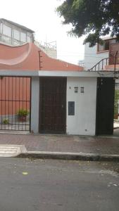 a small white building with a brown door on a street at Colores Hospedaje Miraflores in Lima