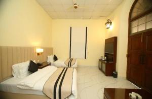 Habitación de hotel con 2 camas y TV en Peshawar Barracks by Shelton's Rezidor en Peshawar